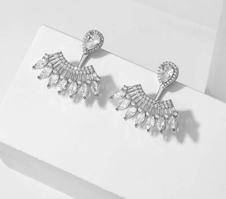 a pair of earrings sitting on top of a white surface