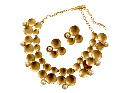 a gold necklace and earrings with pearls on a black background