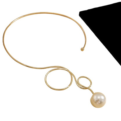 a gold necklace with a pearl on a black background