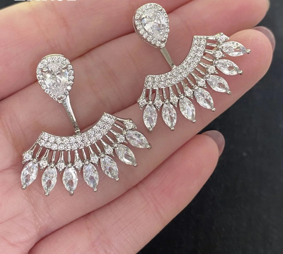 a person holding a pair of earrings in their hand