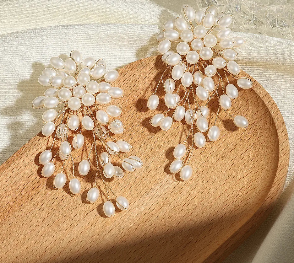 a pair of earrings with pearls on a wooden tray