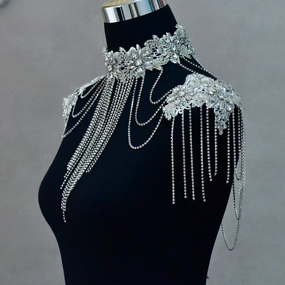 a woman wearing a black dress with silver chains on it