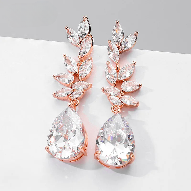 a pair of rose gold tone earrings with crystal drops