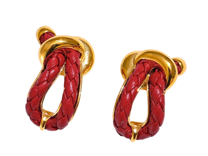 a pair of red and gold earrings on a black background