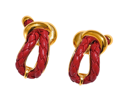 a pair of red and gold earrings on a black background