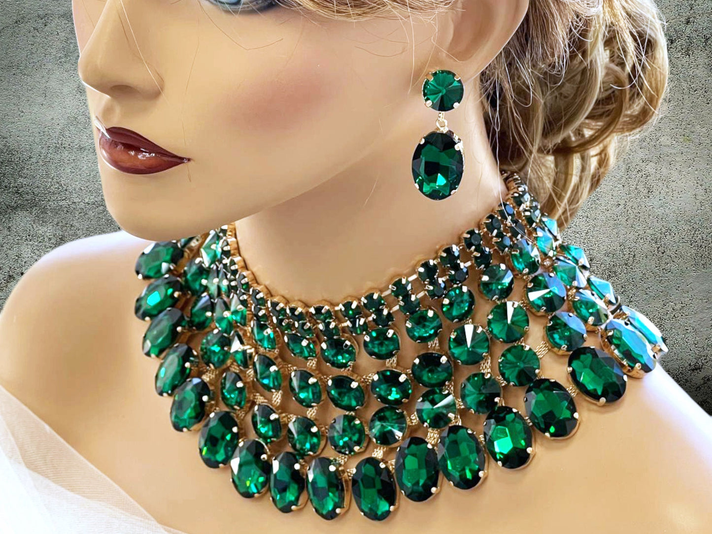 a woman wearing a green necklace and earrings