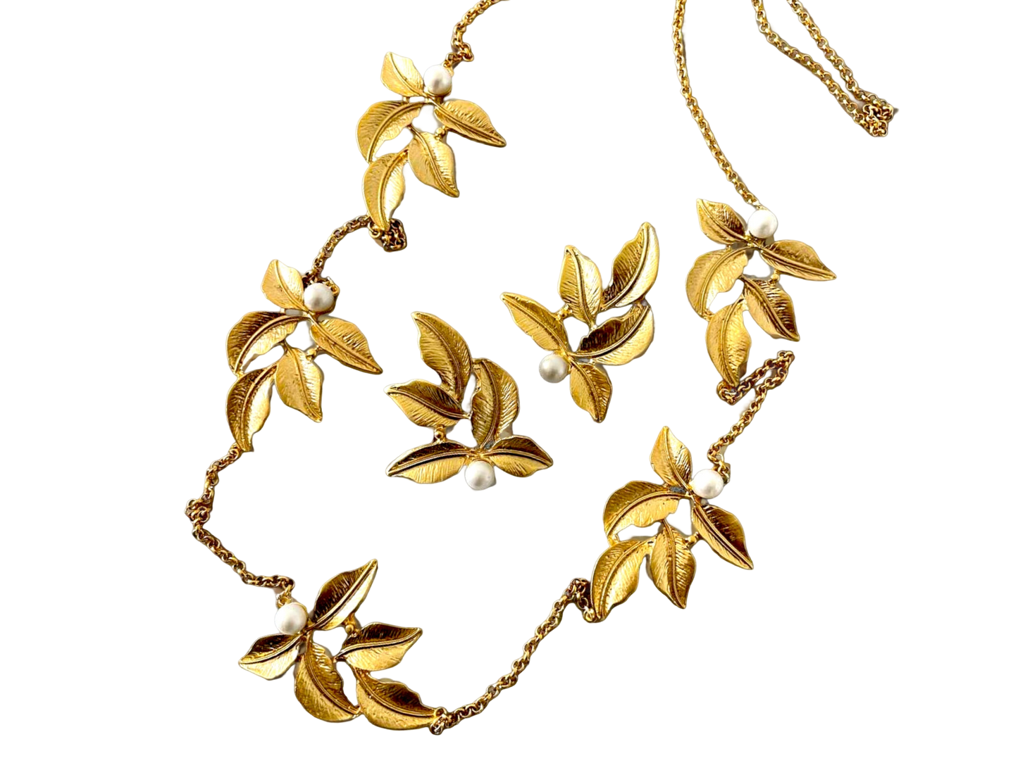 a gold necklace with flowers and pearls on a black background