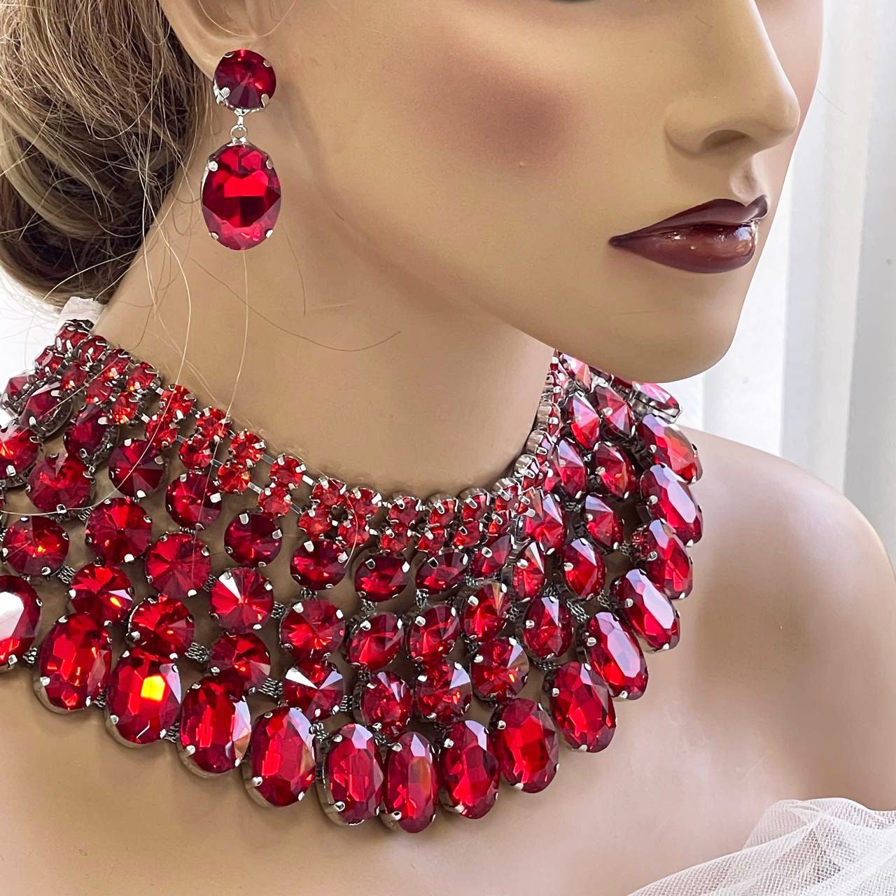 a woman wearing a red necklace and earrings