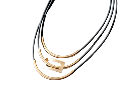 three black and gold necklaces on a black background