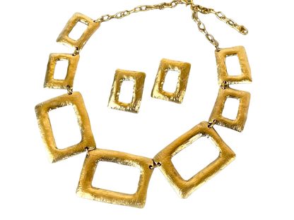 a gold necklace and matching earrings on a black background