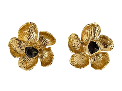 a pair of gold flower earrings with black stones