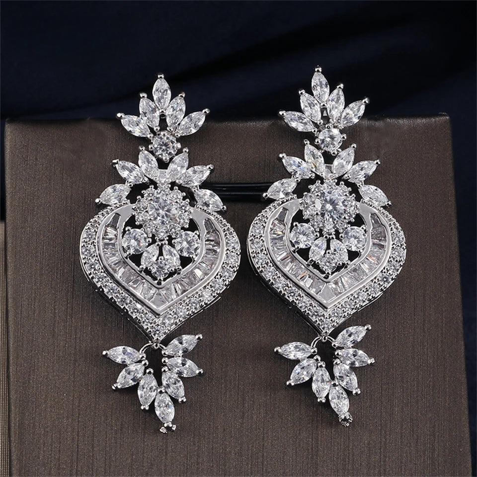 a pair of diamond earrings on top of a piece of cloth