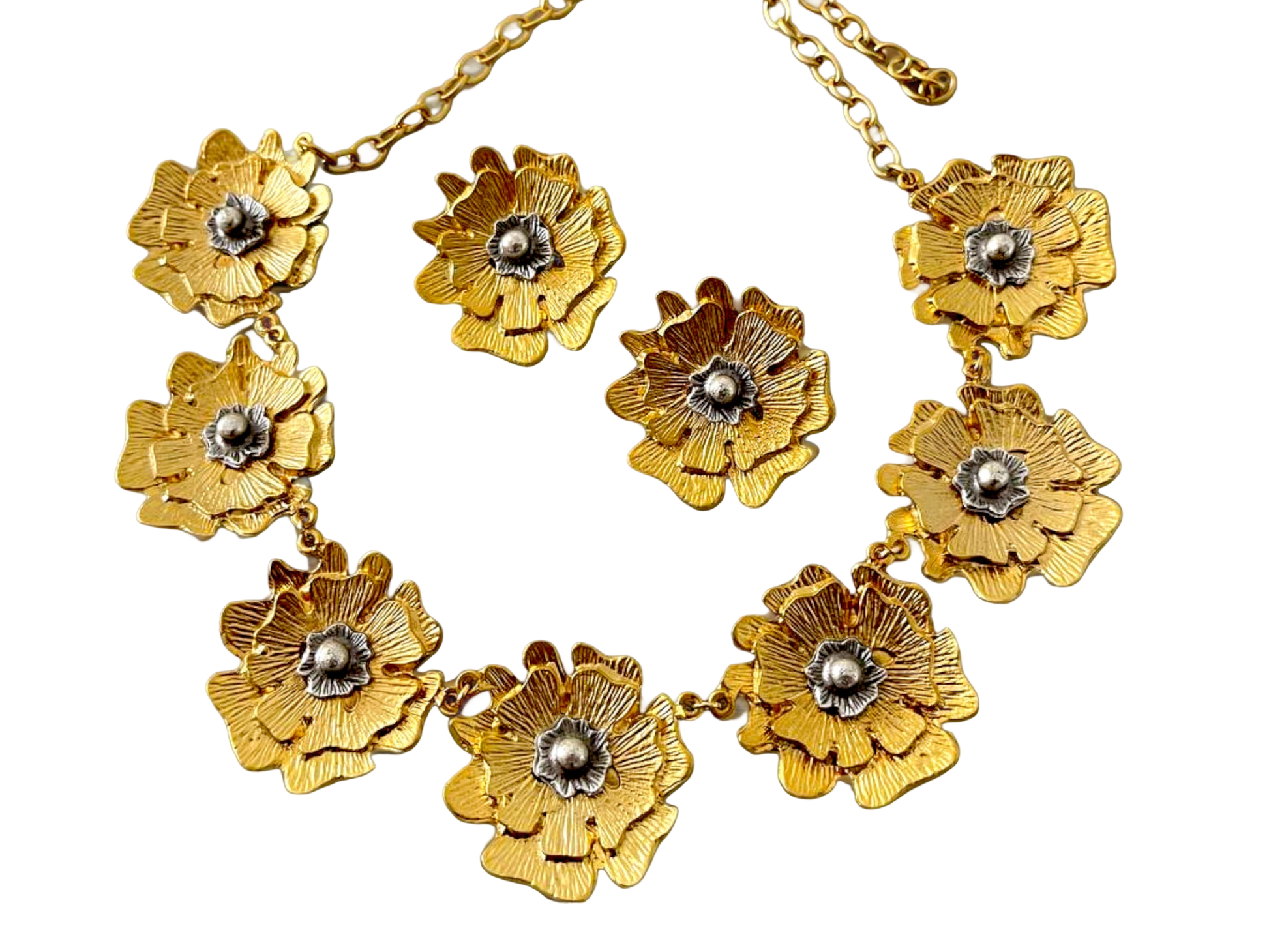 a gold necklace with flowers on a black background